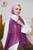 A woman wearing a white long-sleeve top, brown pants, and a dual-tone purple and white hijab scarf, posed against a soft beige background with a decorative logo in the top-left corner.